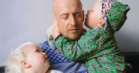 Bald Father Bonding with Children in Colorful Attire at Home