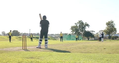 Cricketer in Action at Sunlit Field Preparing to Bat