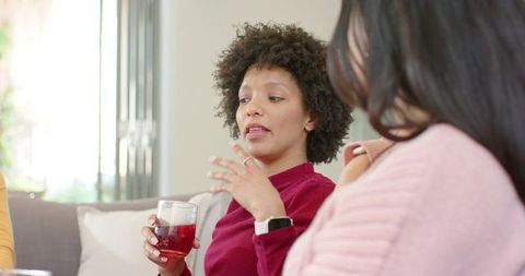 Women enjoying cozy conversation over red drinks on modern minimalist living room couch