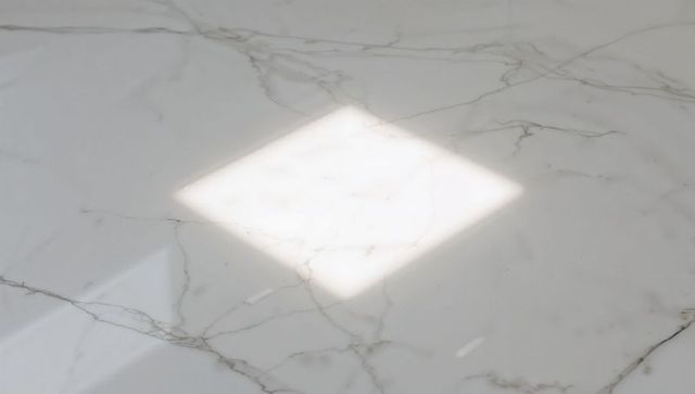 Sunlight diamond patch on polished white marble slab with subtle veining and reflection