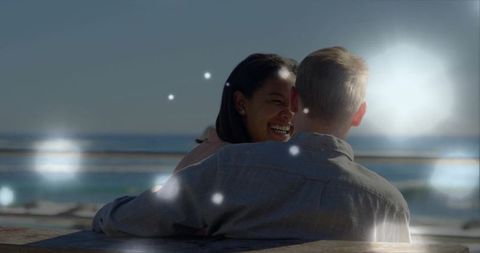 Laughing couple embracing by sunny seaside