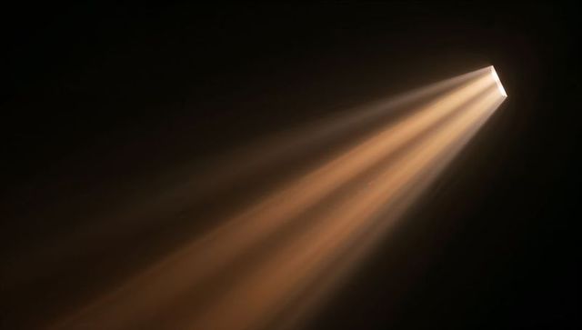 Warm diagonal light beams streaming through rectangular slit with dust and haze