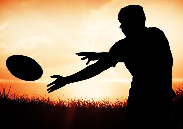 Digital composition of player silhouette catching rugby ball against sunset in background