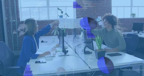 Two coworkers sharing chart across desk divider in bright loft office for team collaboration