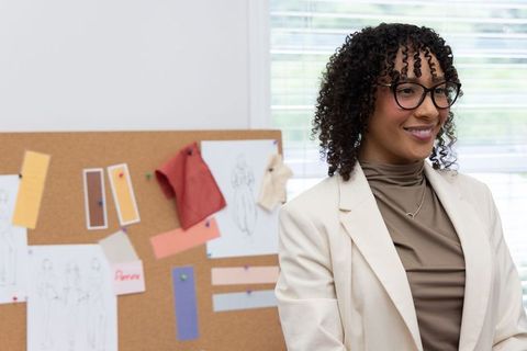African american fashion designer reviewing moodboard with sketches and fabric swatches