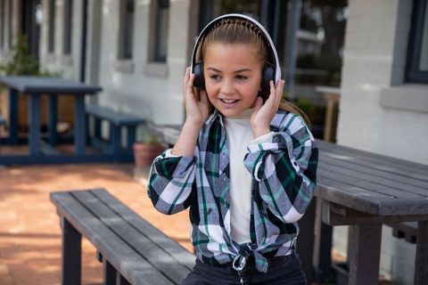 Young Girl Enjoying Music with Headphones on Outdoor Patio