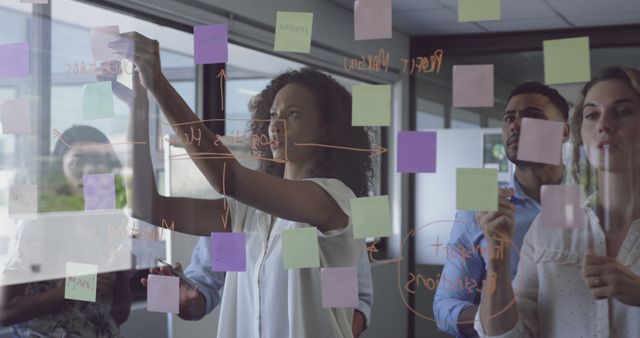 Diverse office team brainstorming with handwritten diagrams on glass walls - Download Free Stock Images Pikwizard.com