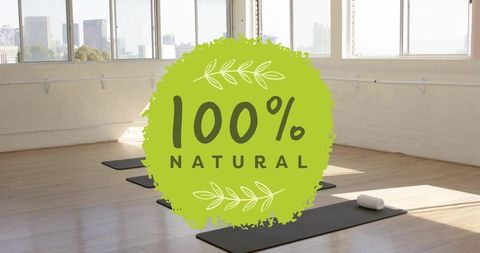 100% natural badge over minimalist yoga studio interior with mats, towel and city view