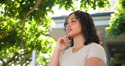 Thoughtful woman in natural light under tree canopy