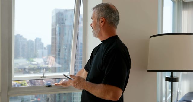 Middle Aged Man Looking Out City Window Holding Smartphone - Download Free Stock Images Pikwizard.com