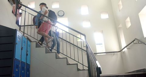 Teen Boys Socializing on School Stairs with Lockers Around