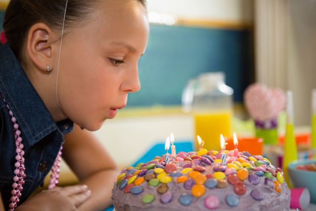 Girl blowing out the candles on a birthday cake at home