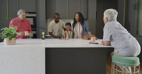 Multigenerational diverse family gathering at modern kitchen island celebrating child trophy