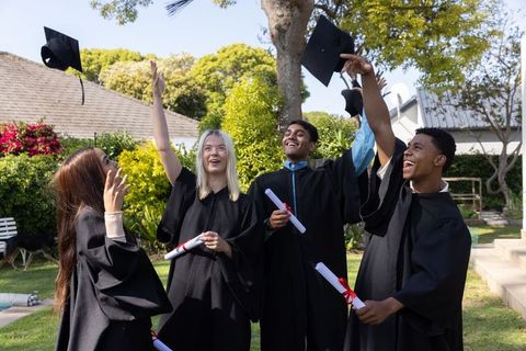 Diverse graduates celebrating graduation success outdoors