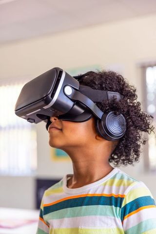 African american child exploring virtual reality wearing headset and headphones at home