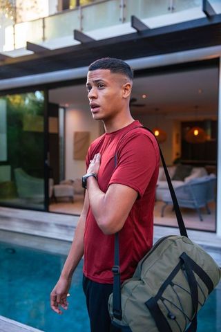 Young Man with Duffel Bag by Poolside Recreational Area, Stylish Leisure
