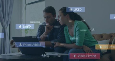 Couple Browsing Laptop with Social Media Icons Indoors