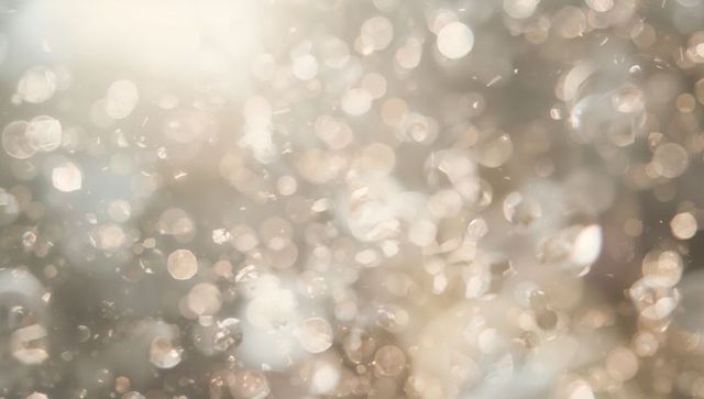 Warm golden bokeh sparkle background with floating glitter, soft prism light