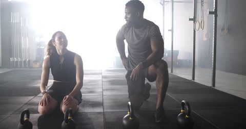 Diverse workout partners discuss fitness routine in gym