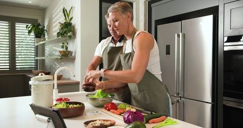 Senior Couple Preparing Salad with Tablet Assistance in Modern Kitchen