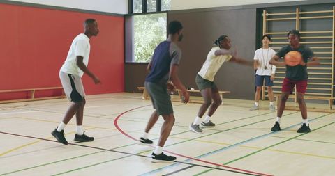 High school basketball training with asian coach blowing whistle in indoor gymnasium