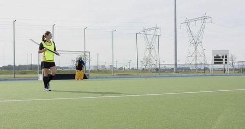 Female hockey players on synthetic turf field preparing for practice