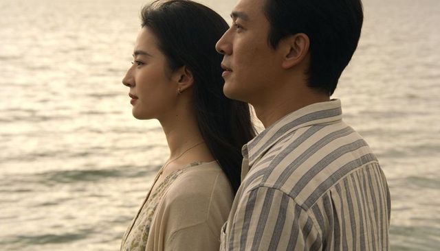 Serene couple standing shoreline gazing toward horizon at golden hour, contemplative duet