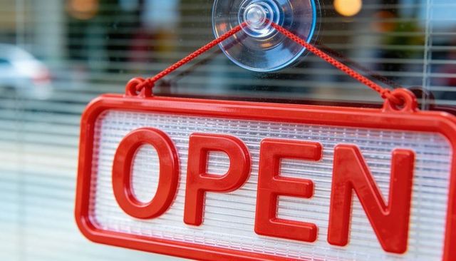 Hanging red open sign on glass storefront with suction cup, red cord and urban reflections
