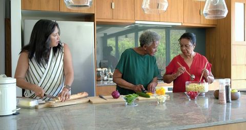 Multigenerational african american women preparing meal together in modern bright kitchen