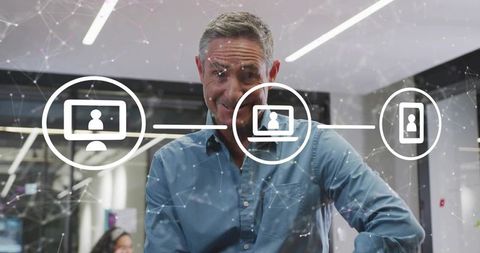 Mature manager leaning and interacting with holographic network interface, modern office