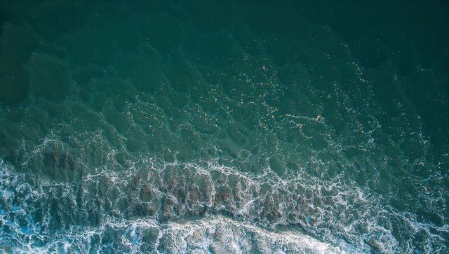 Sunlight sparkling over breaking surf crashing over sandbar aerial ocean waves coastal