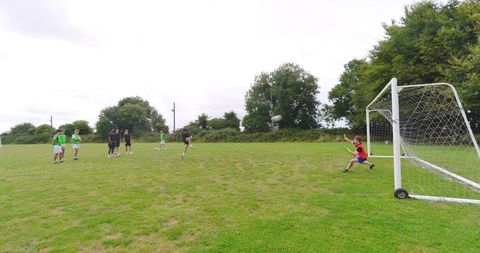 Teenager kicking ball towards goal on grass soccer field