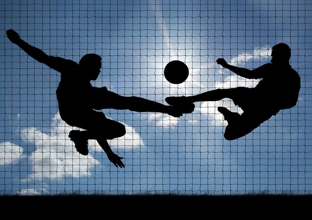 Silhouettes of two soccer players kicking a ball against a bright sky with a net in the background. Ideal for use in sports-related content, advertisements, motivational posters, and articles about teamwork and athleticism.