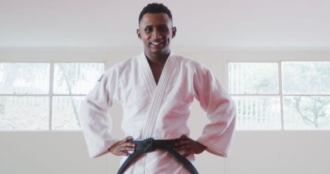 Confident biracial teenage judoka smiling in gym