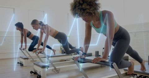 Focused Women Enjoying Group Reformer Pilates Session with Wearable Tech