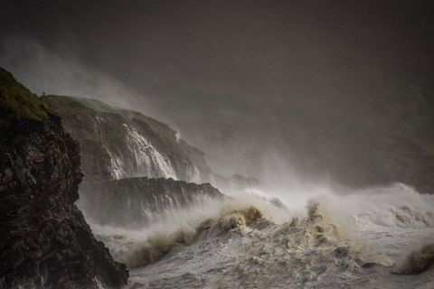 Storm Waves Crashing Against Rugged Coastal Cliffs and Cascading Waterfalls