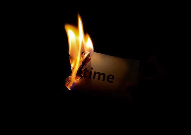 Burning sheet with 'time' written on it, flame consuming the edges. Great for concepts about limited time, deadlines, urgency, and fleeting moments. Ideal for use in articles, presentations, and motivational materials emphasizing time's passage or wasted opportunities.