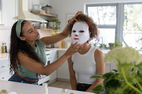 African american women applying led facial mask during bright at-home skincare routine