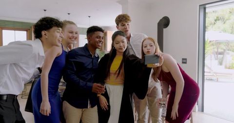 Diverse friends taking selfie at home party in semi-formal attire celebrating together