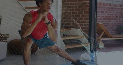 Performing deep lateral lunge during home workout wearing red top and blue shorts