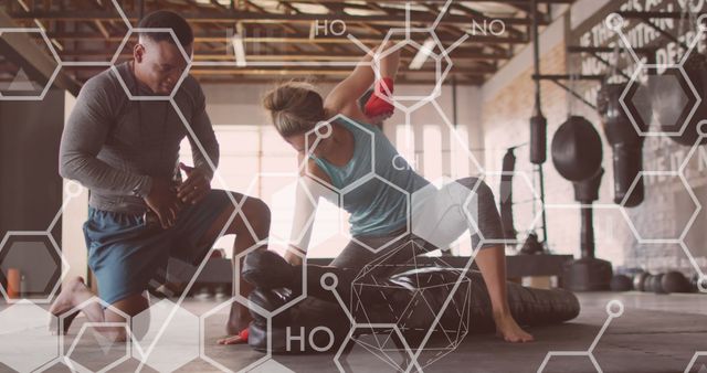 Personal trainer assisting woman with a fitness routine in a gym, specifically using a tire for strength training. This can be used for advertisements or promotions related to personal training, fitness programs, gym memberships, or health and wellness campaigns.