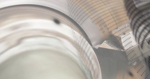 Glass rim reflecting on perforated metal plate with threaded rod industrial closeup