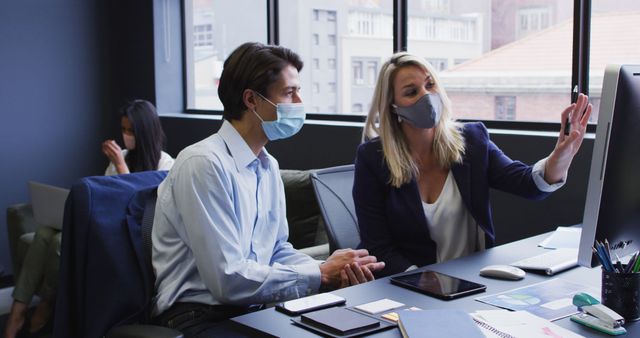 Diverse business people wearing face masks using computer in office - Download Free Stock Photos Pikwizard.com