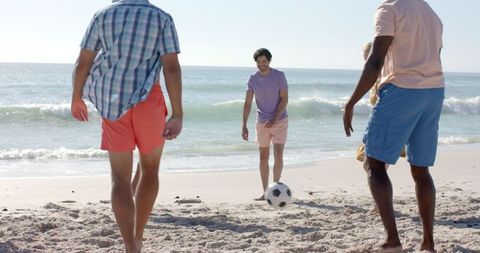 Adults Playing Soccer on Sunny Beach in Summer