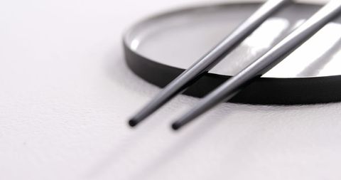 Precision tweezers with magnifying glass on white surface