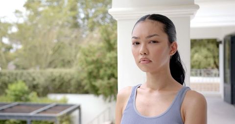Serious Young Woman in Garden with Modern Architecture