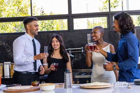 African american friends toasting in modern kitchen with pizza and wine celebrating