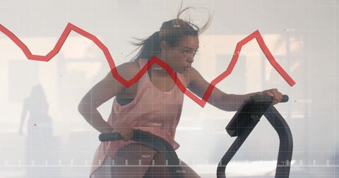 Woman cycling stationary bike with overlay of stock market graph