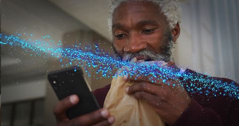 Senior Man Enjoying Pastry with Digital Connection in Home Kitchen
