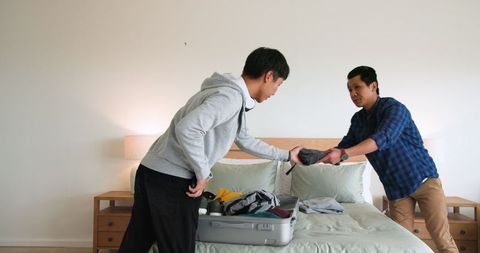 Father and Son Packing Luggage for Family Trip in Cozy Bedroom
